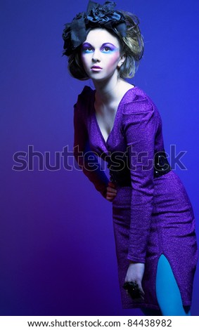 Portrait of young stylish woman in violet dress and little black hat