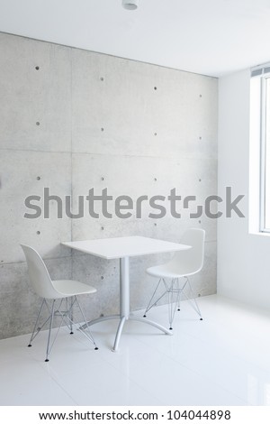 white table and chair against concrete wall