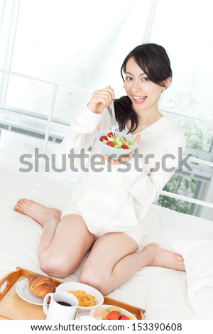 beautiful young woman eating breakfast in bed