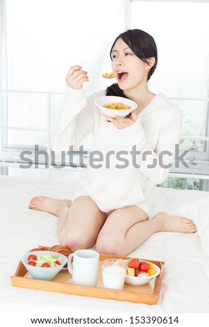 beautiful young woman eating breakfast in bed