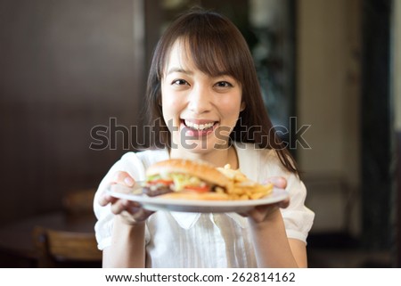 young woman eating hamburger at restaurant