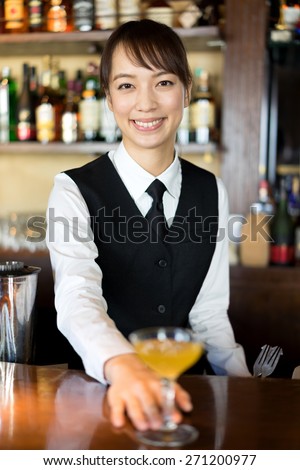 female bartender serving cocktail at bar