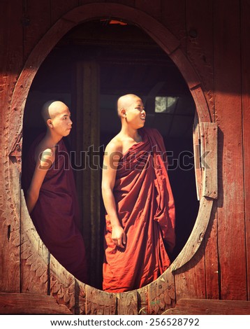 INLE LAKE, MYANMAR - FEBRUARY 02: Young monks are watching from monastery oval window on February 02, 2011 in Shwe Yaunghwe monastery in Nyaungshwe, Shan state of Myanmar