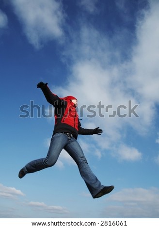 Happiness girl in red clothitg jump on blue background