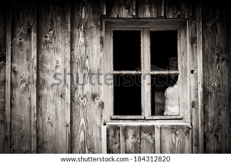 Horror scene of a scary woman. Mysterious woman staring out the window.