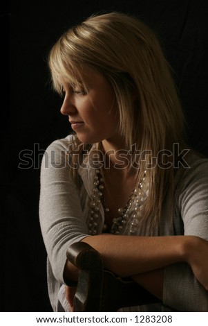 Low key colour image of blonde young woman in profile.