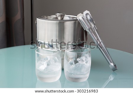 Glass of cold water and ice with stainless bucket