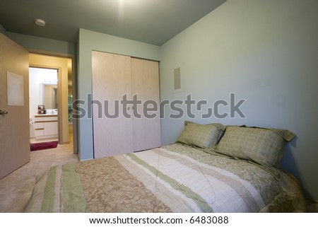 View of simple bedroom with bathroom through door