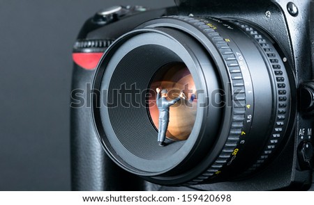Miniature man cleaning camera lens. Macro photo