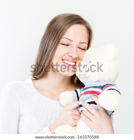 Charming brunette embraces teddy bear, isolated on white background