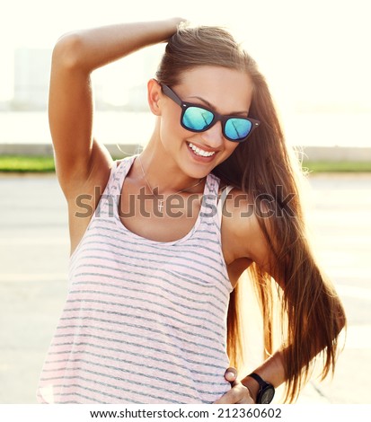 young sexy girl standing on the street over sunset wearing trendy sunglasses.