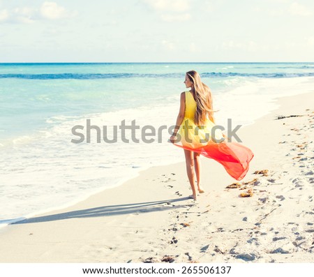 Beautiful tanned fashion sexy girl in glamorous dress posing on the beach on her amazing vacation