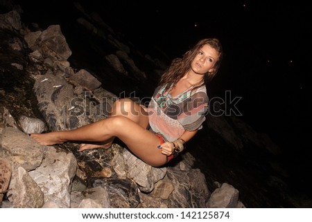 Attractive woman in a wet dress sitting by the river in the evening