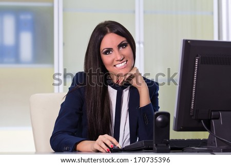 Young happy business woman working on a computer at office