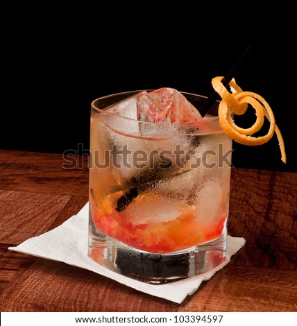whiskey old fashioned with cherries and orange isolated on a black background