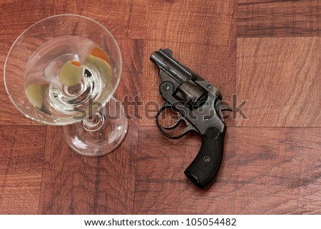 closeup of an old hand gun on a table with a martini out of focus