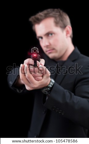 Young man pointing a gun with a laser only the front of the gun in focus