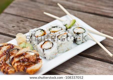 Sushi rolls served on a picnic table, some fried some rice rolls