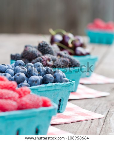 fresh berries for sale placed on a table in a row, blueberries in focus with shallow depth of field
