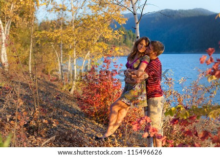 adorable portrait of a young couple by the lake with changing foliage