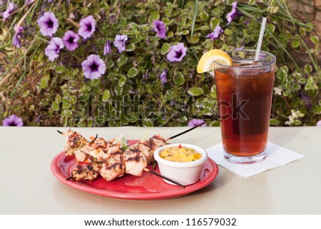 grilled chicken skewers served on a red plate with a mango salsa