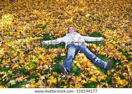 Beautiful woman making angels in bright  leaves mid autumn in idaho