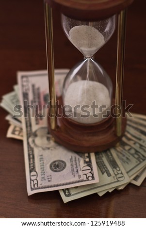 concept of an hour glass with time passing over money