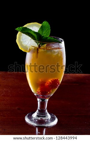 raspberry iced tea garnished with a lemon wheel on a dark bar