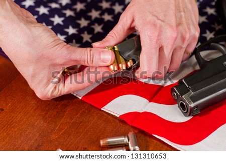 female hands loading a hand gun with hallow point bullets and an american flag in the background