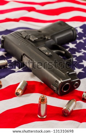closeup of a hallow point bullet with a gun and an American flag fading to a shallow depth of field