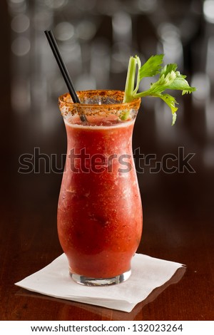 closeup of a bloody mary cocktail garnished with a celery sick isolated on a busy bar top