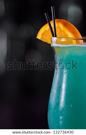 closeup of a blue hawaiian cocktail on a out of focus bar top