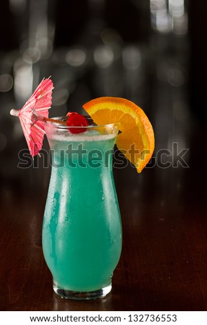 closeup of a blue hawaiian cocktail on a out of focus bar top