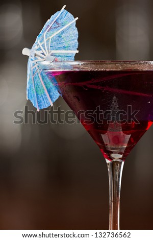 layered drink served on a bar with red on the bottom and blue on top garnished with a parasol