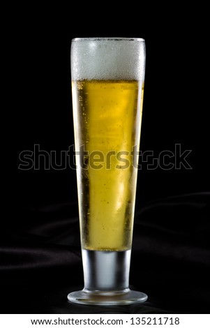 refreshing light beer in a cold glass served on a dark bar