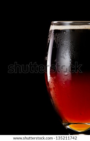 closeup of an irish red ale served in a chalice with half of the pint with a chocolate stout layered on top in a dramatic bar with fog