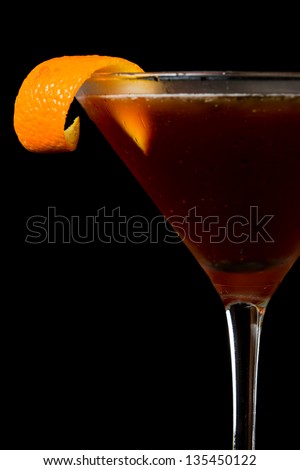 tall espresso martini served on a black bar top garnished with an orange twist