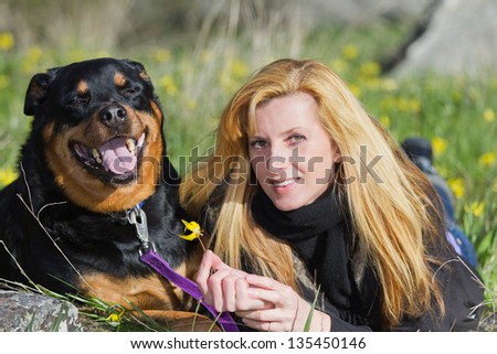 woman and her dog resting in the spring grass with yellow flowers showing affection