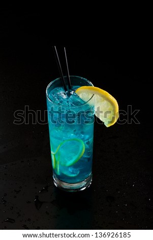 bright blue lemonade served in a tall glass isolated on a black background