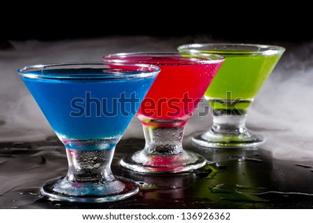 bright mini martinis served on a wet dark bar top with fog for a dramatic effect