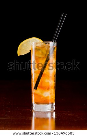 classic cocktail long island iced tea served on a bar and garnished with a lemon slice