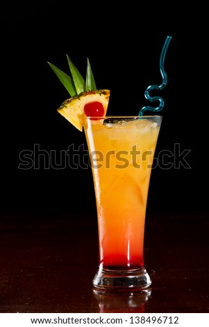 sex on the beach cocktail served on a bar garnished with a pineapple slice and a cherry