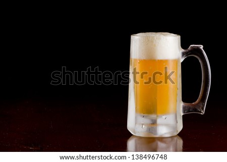 cold beer served in a frozen mug on a bar top isolated on a black background