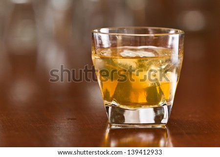 bourbon whiskey served with ice on a out of focus busy bar