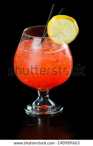 strawberry lemonade isolated on a black background served in a brandy snifter garnished with a lemon wheel