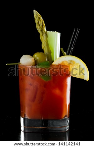 spicy Bloody Mary served on a dark bar garnished with pickled veggies and a lemon