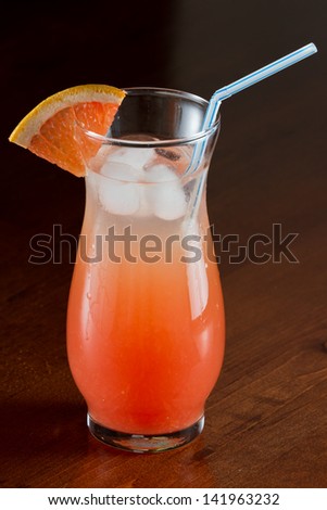 fresh pressed ruby red grape fruit juice served on a wooden bar with a fresh slice of fruit