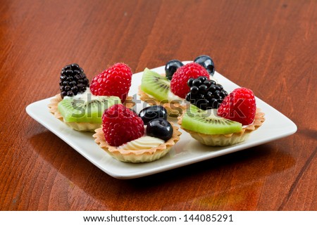 bite size fruit tarts with fresh fruit served on a white plate