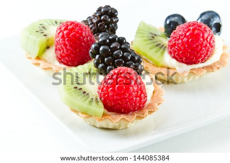 bite size fruit tarts with fresh fruit served on a white background