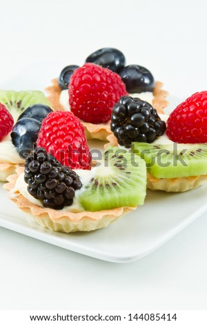 bite size fruit tarts with fresh fruit served on a white background